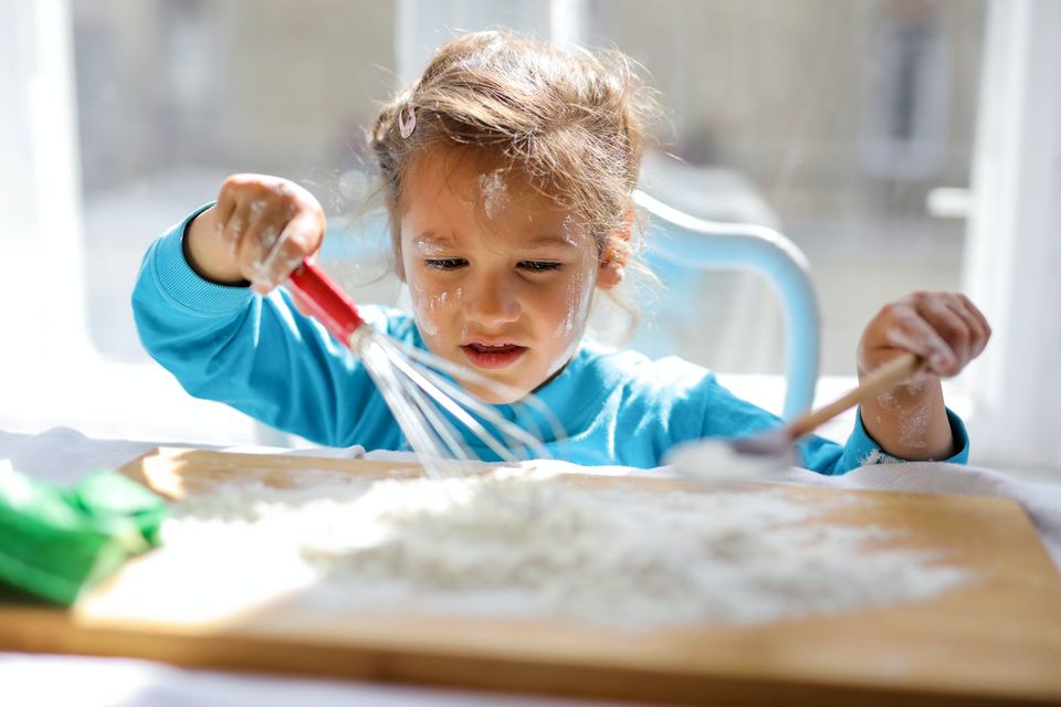 Young girl baking with whisk and wooden spoon