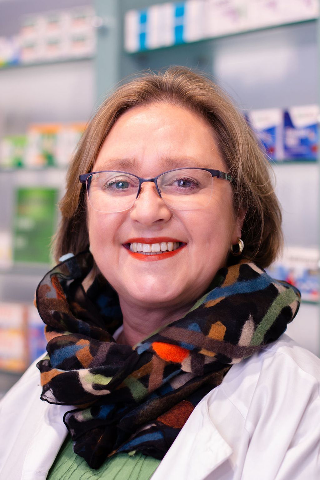 Eine Frau mit Brille und Schal lächelt in die Kamera