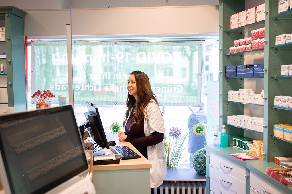 Eine Frau steht in einer Apotheke vor einem Computer.