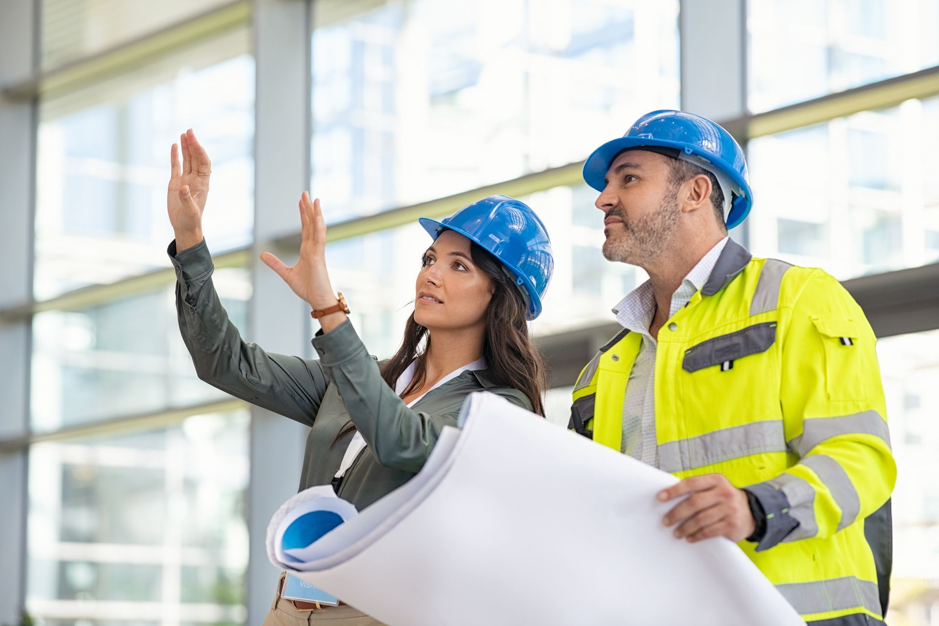 A man and a woman are looking at a blueprint in a building.