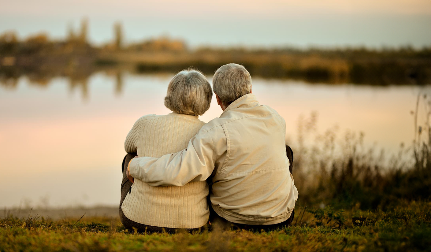 Green notebook with pen, candle, and preserved plant on a wooden surface.