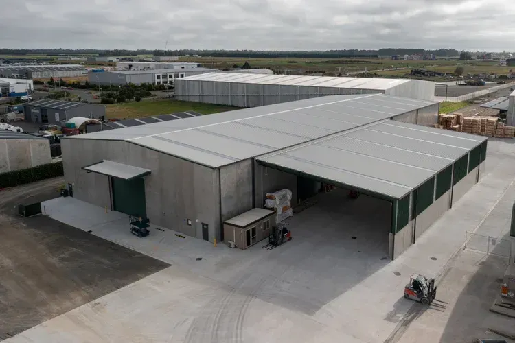 Large industrial building with gray walls and roof, covered loading dock. Exterior setting.
