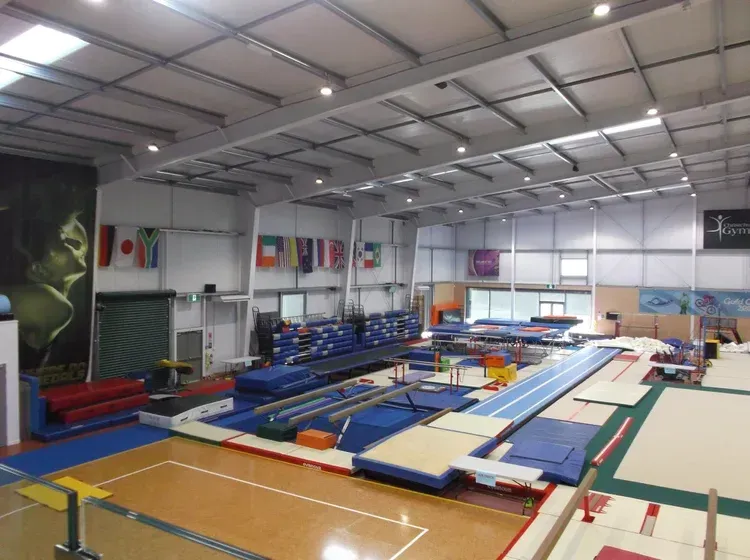 Gymnasium interior, with gymnastics equipment and various mats.