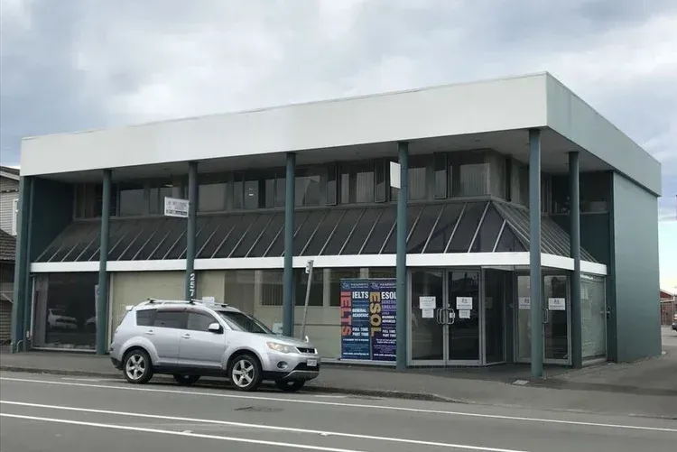Silver SUV parked in front of a two-story commercial building with large windows and support columns.