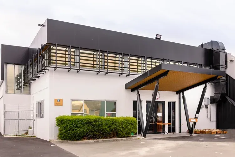 White and black modern building exterior with entrance canopy and windows.