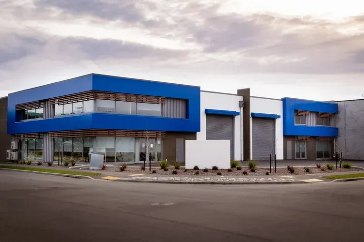 Modern commercial building with blue accents, glass windows, and a corner lot on a gray street.