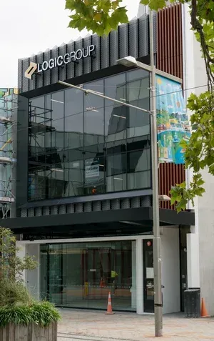 Office building of Logic Group, dark glass and metal facade, gray sky, street scene.