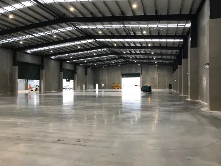 Large, empty warehouse interior with a concrete floor, metal roof, and several open loading doors.