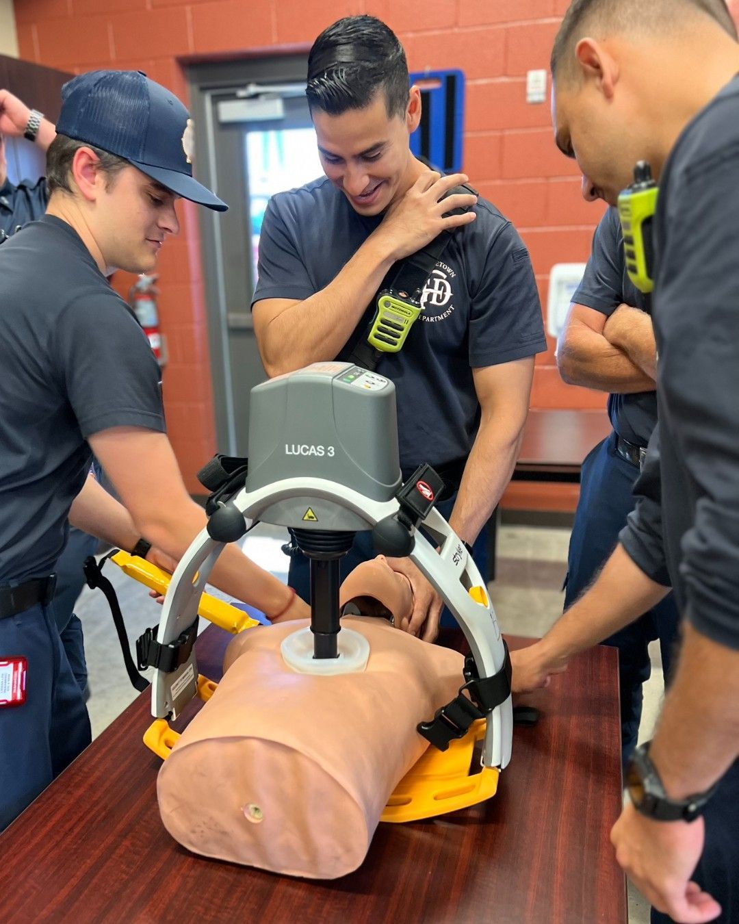 A group of firefighters are training with a Lucas device on a mannequin