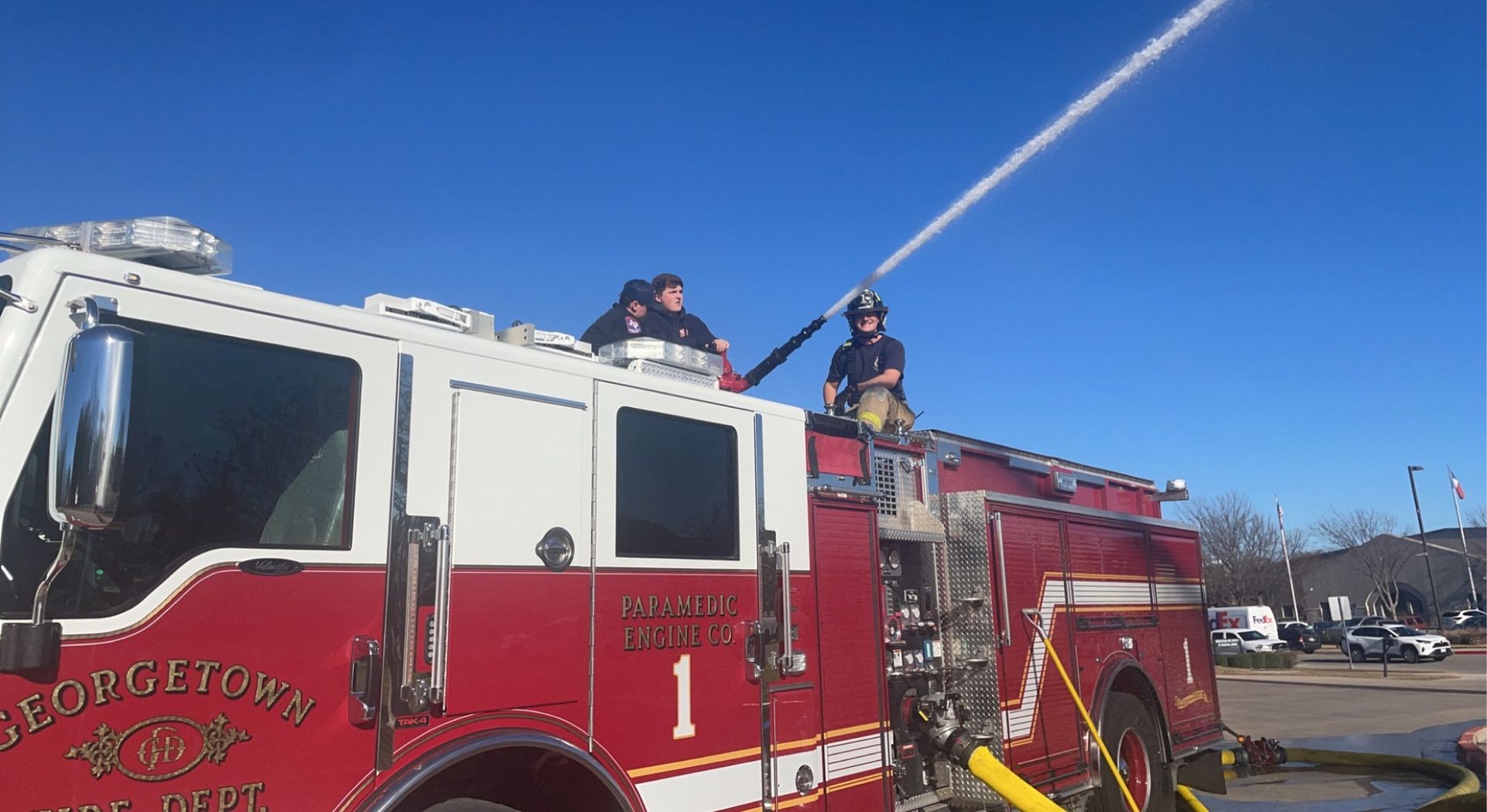 A fire engine with fire fighters spraying water from the top