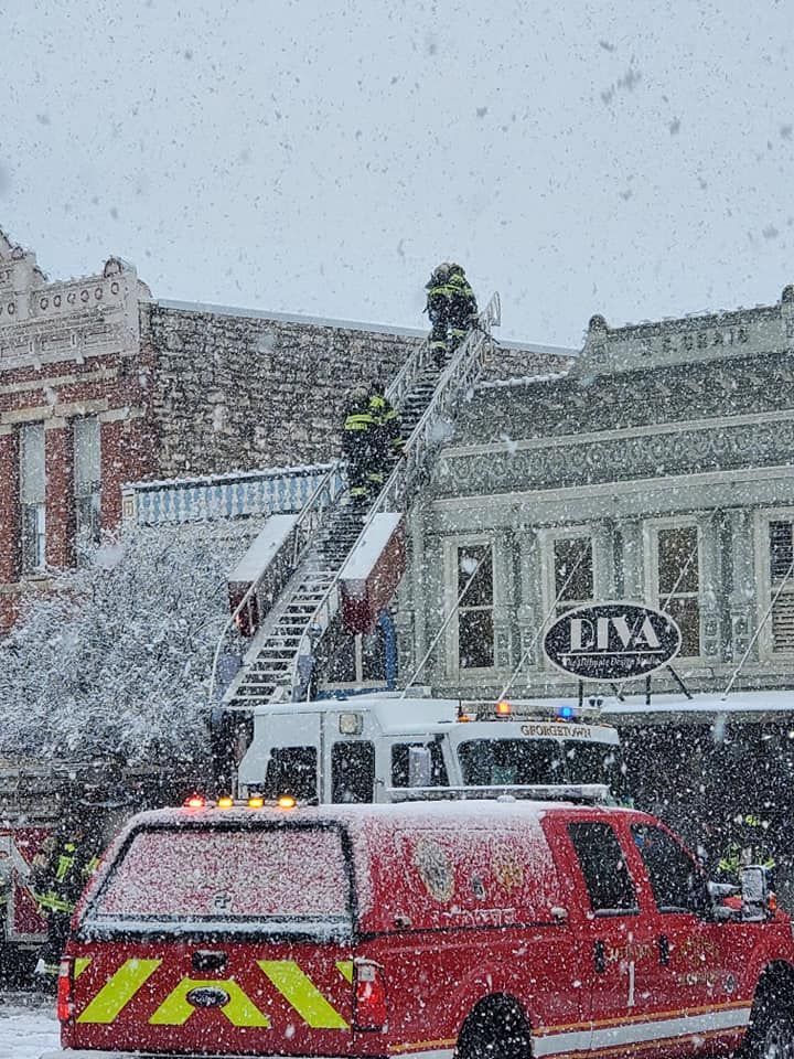 A fire truck is parked in front of a building in the snow.