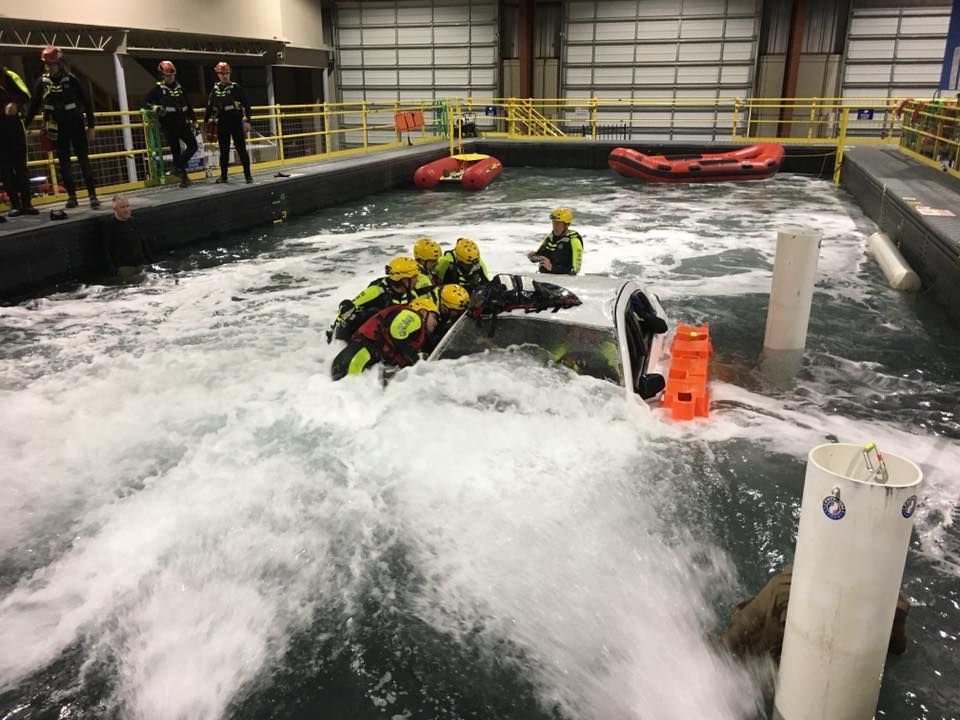 A group of fire fighters are training on swift water reescue a pool of water.