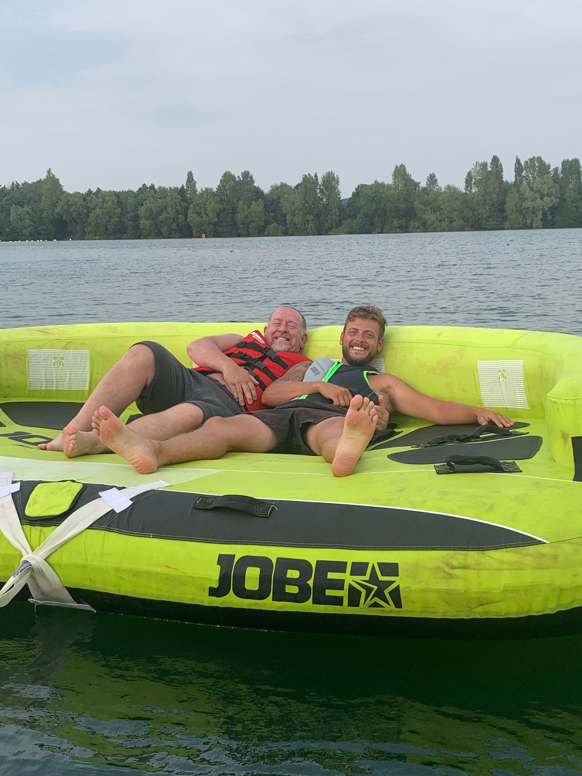 Two men are laying on a jobe boat in the water.