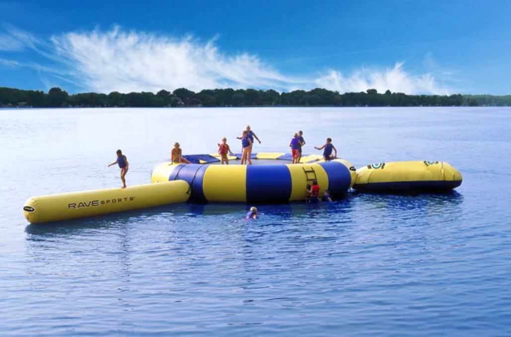 A group of people are playing on a large inflatable raft in the water.