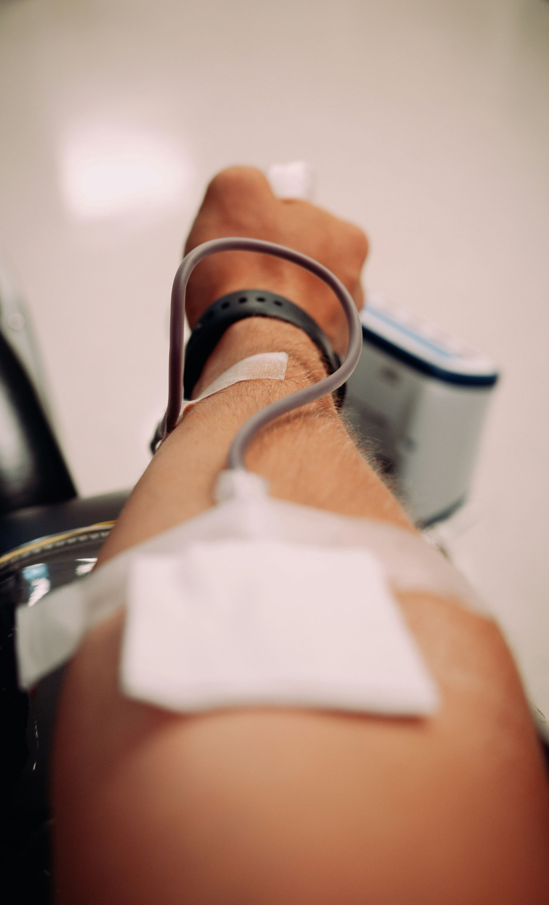 Arm extended with IV line and adhesive bandage in a clinical setting