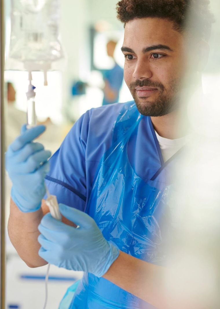 Laboratory technician in blue gloves holding a test tube beside IV equipment