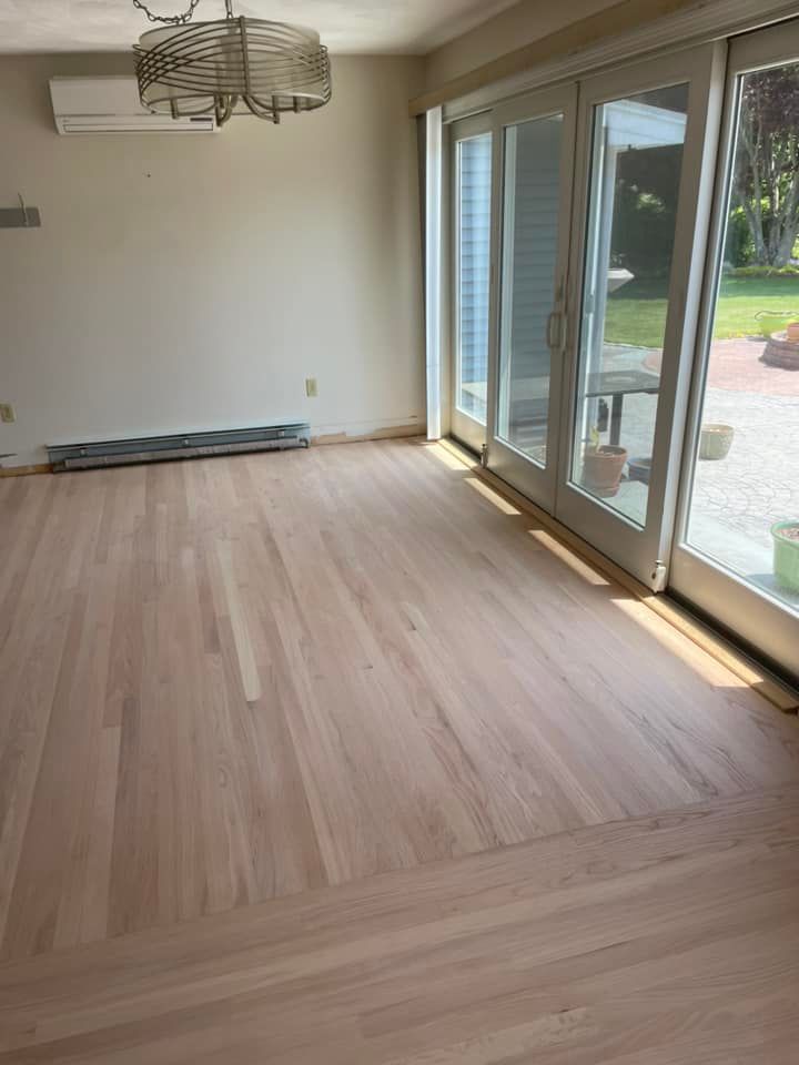An empty living room with hardwood floors and sliding glass doors.