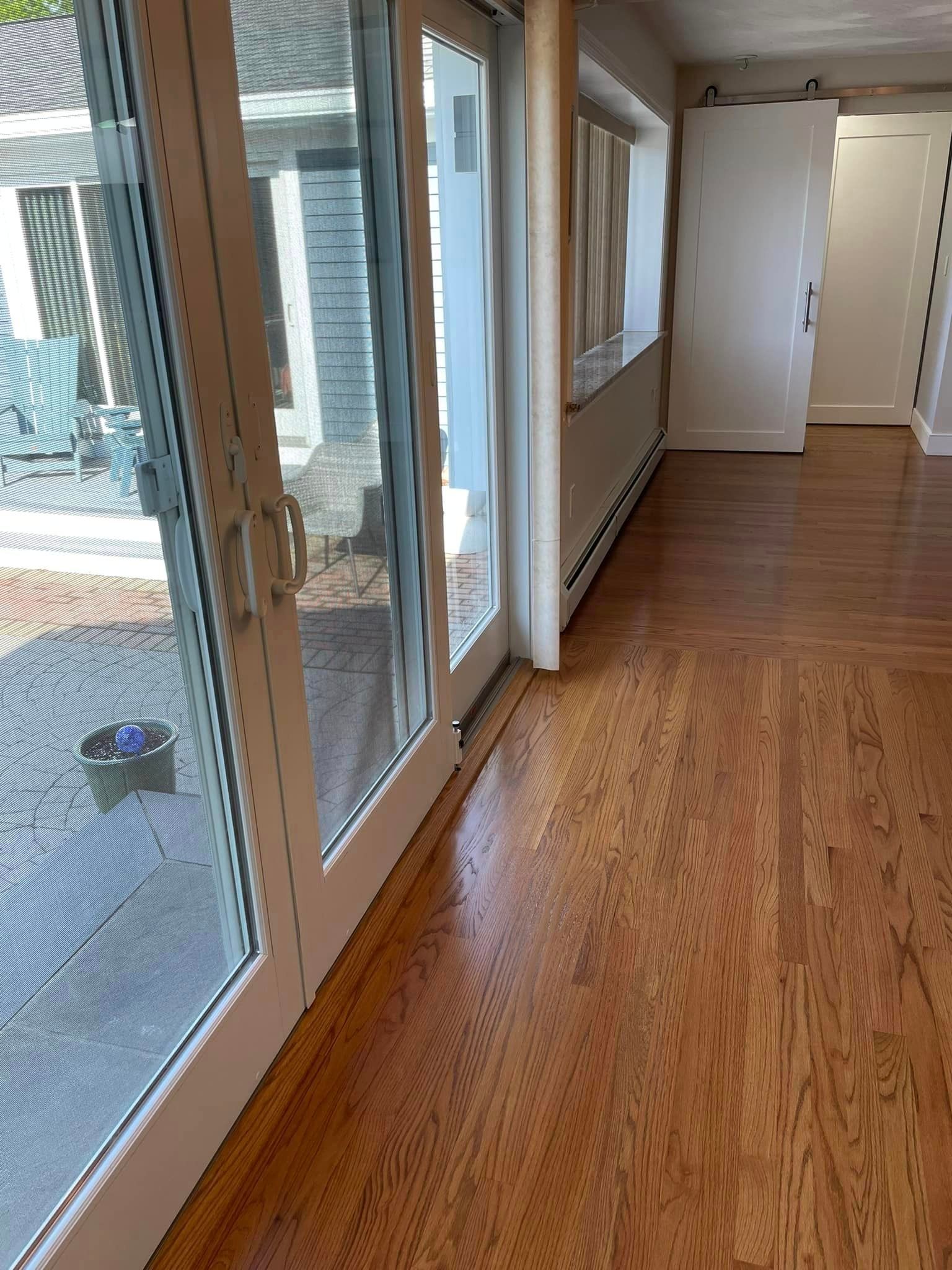 A hallway with hardwood floors and sliding glass doors leading to a patio.