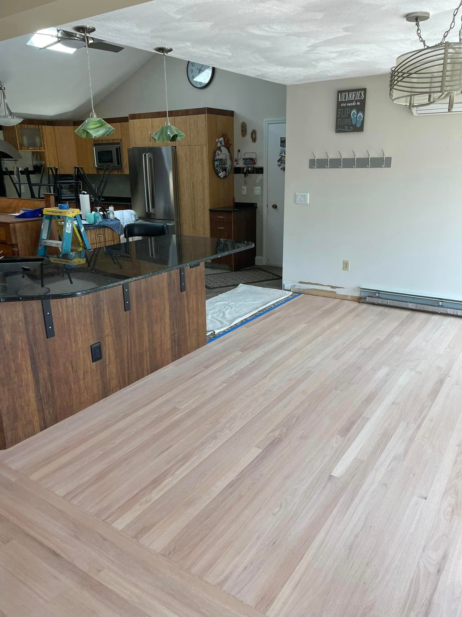 A kitchen with a wooden floor and a stainless steel refrigerator.
