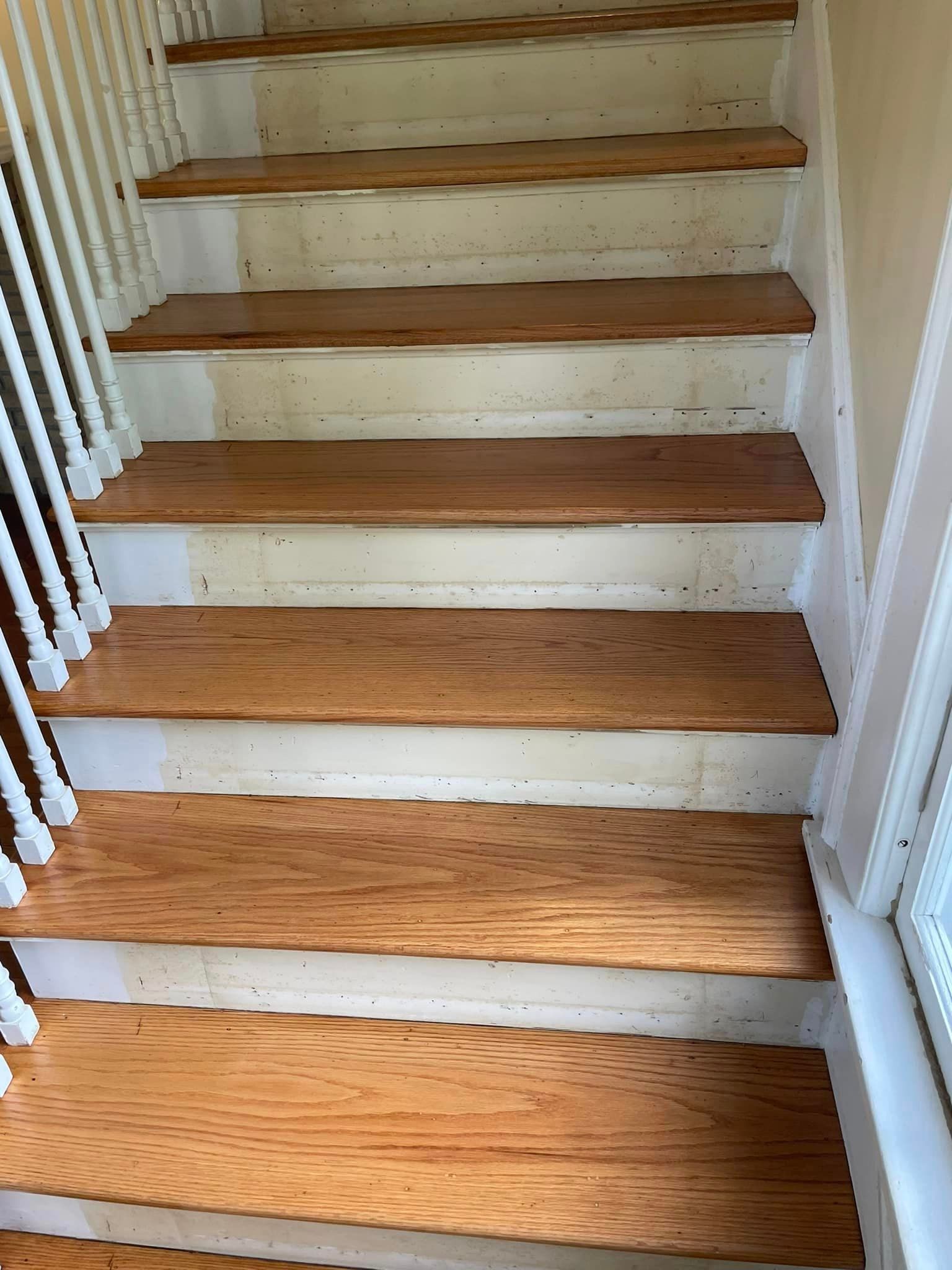 A set of wooden stairs with white railings in a house.