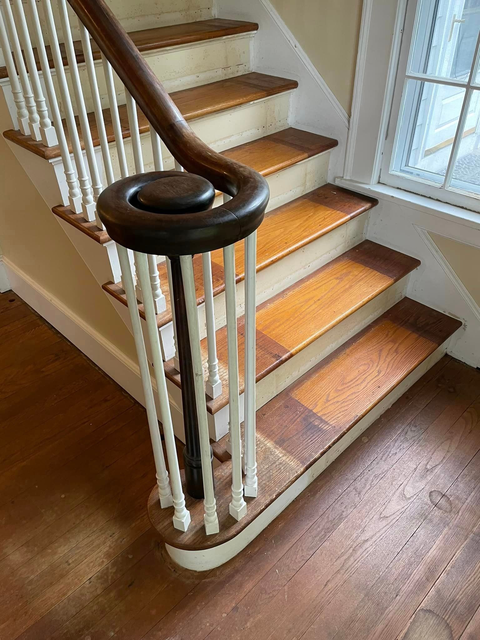 A close up of a wooden staircase with a white railing.
