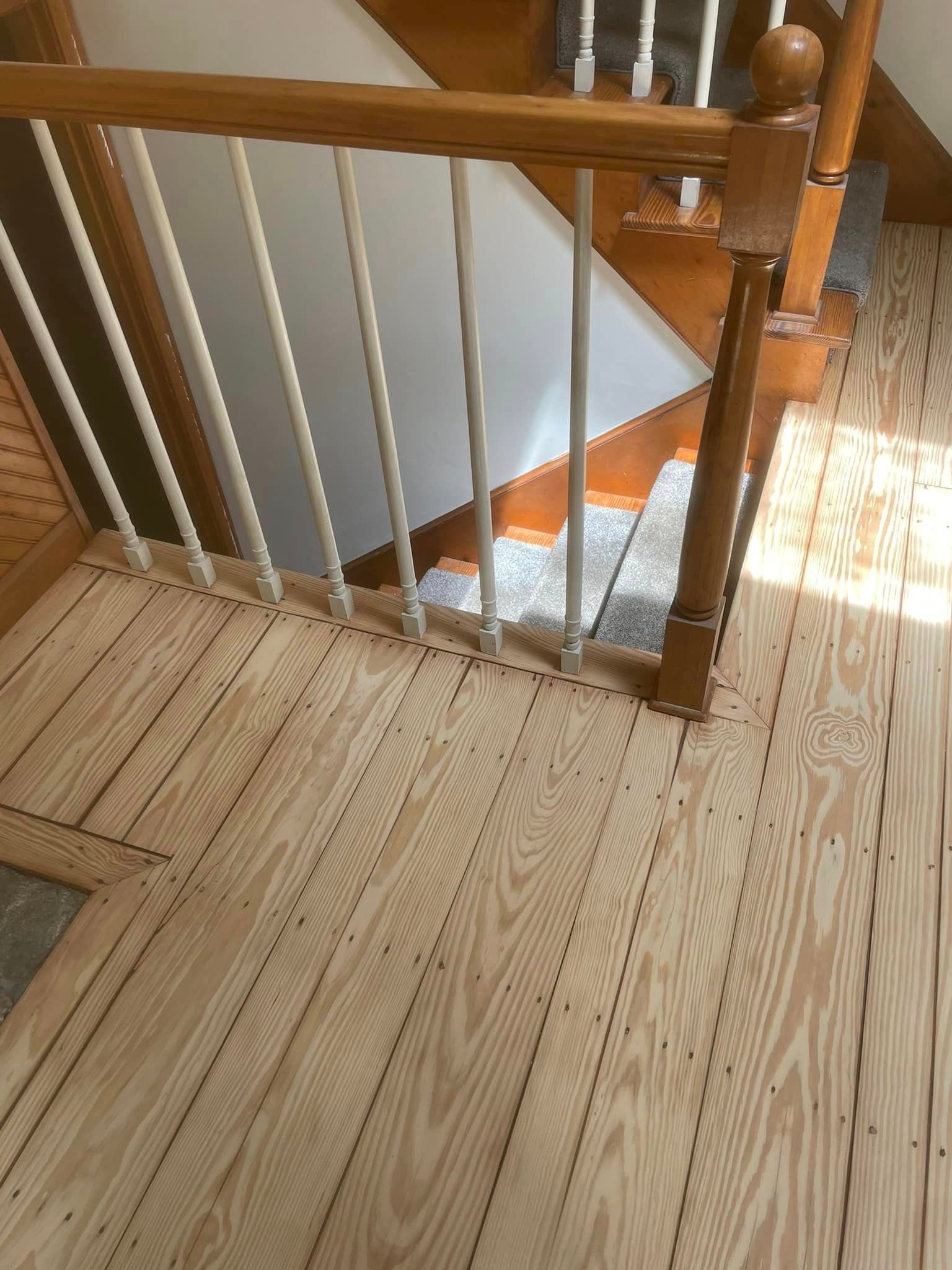 A wooden staircase with a white railing and a wooden floor.