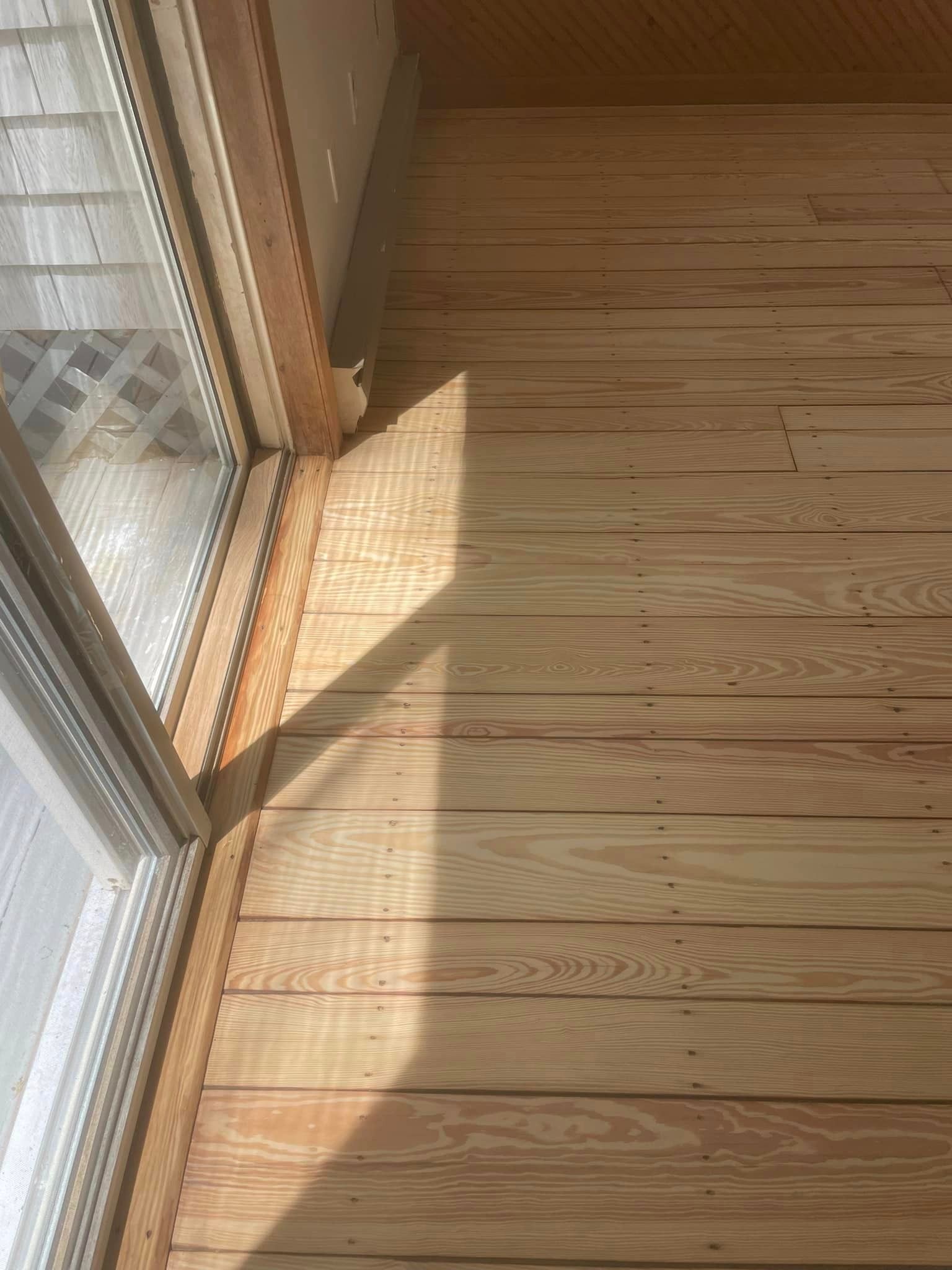 A wooden floor next to a sliding glass door in a room.