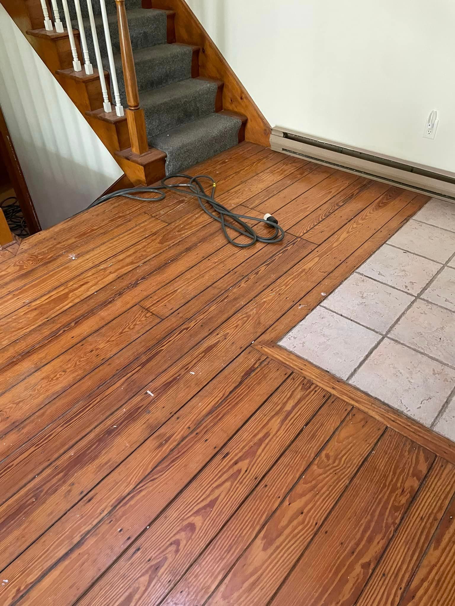 A wooden floor with a staircase in the background.