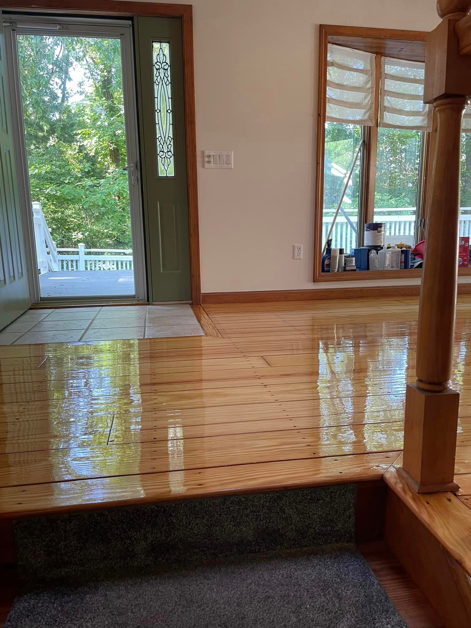 A living room with a wooden floor and stairs leading to a sliding glass door.
