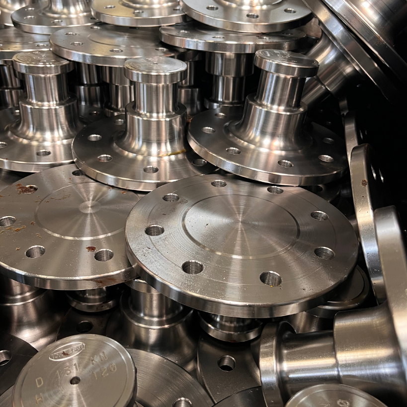 Pila de bridas de acero inoxidable brillantes con ejes centrales elevados y orificios para pernos.