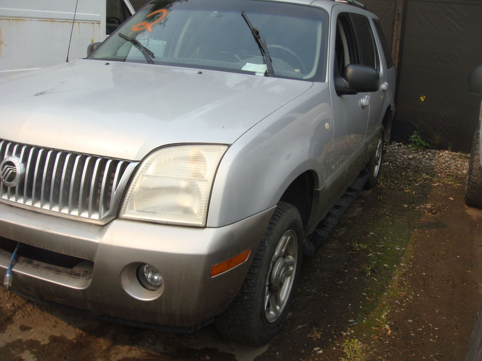 A silver mercury mountaineer is parked in front of a building
