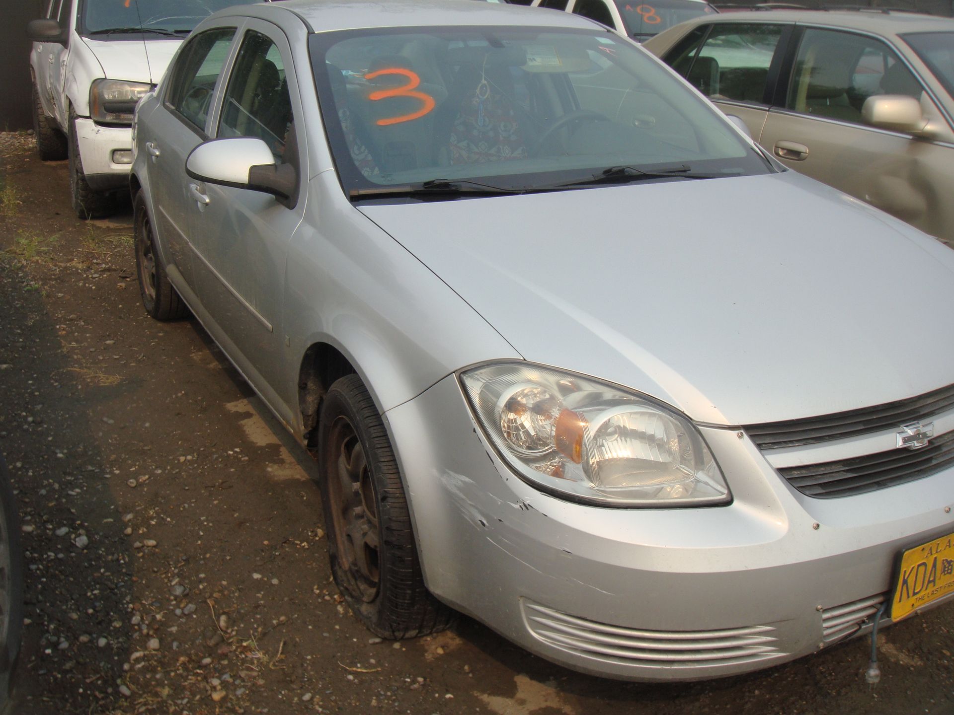 A silver car with the number 3 on the windshield