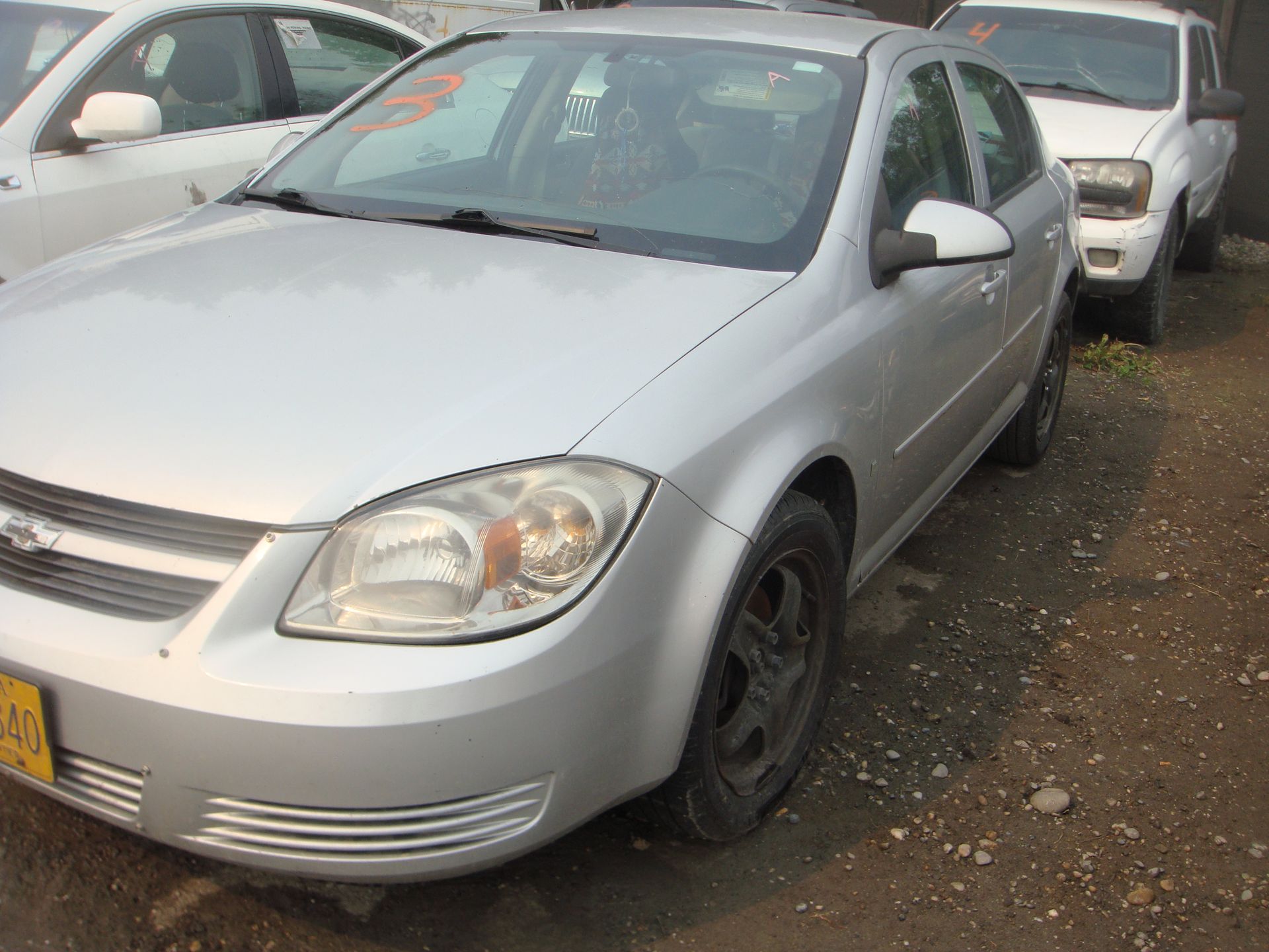 A silver car is parked next to a white car