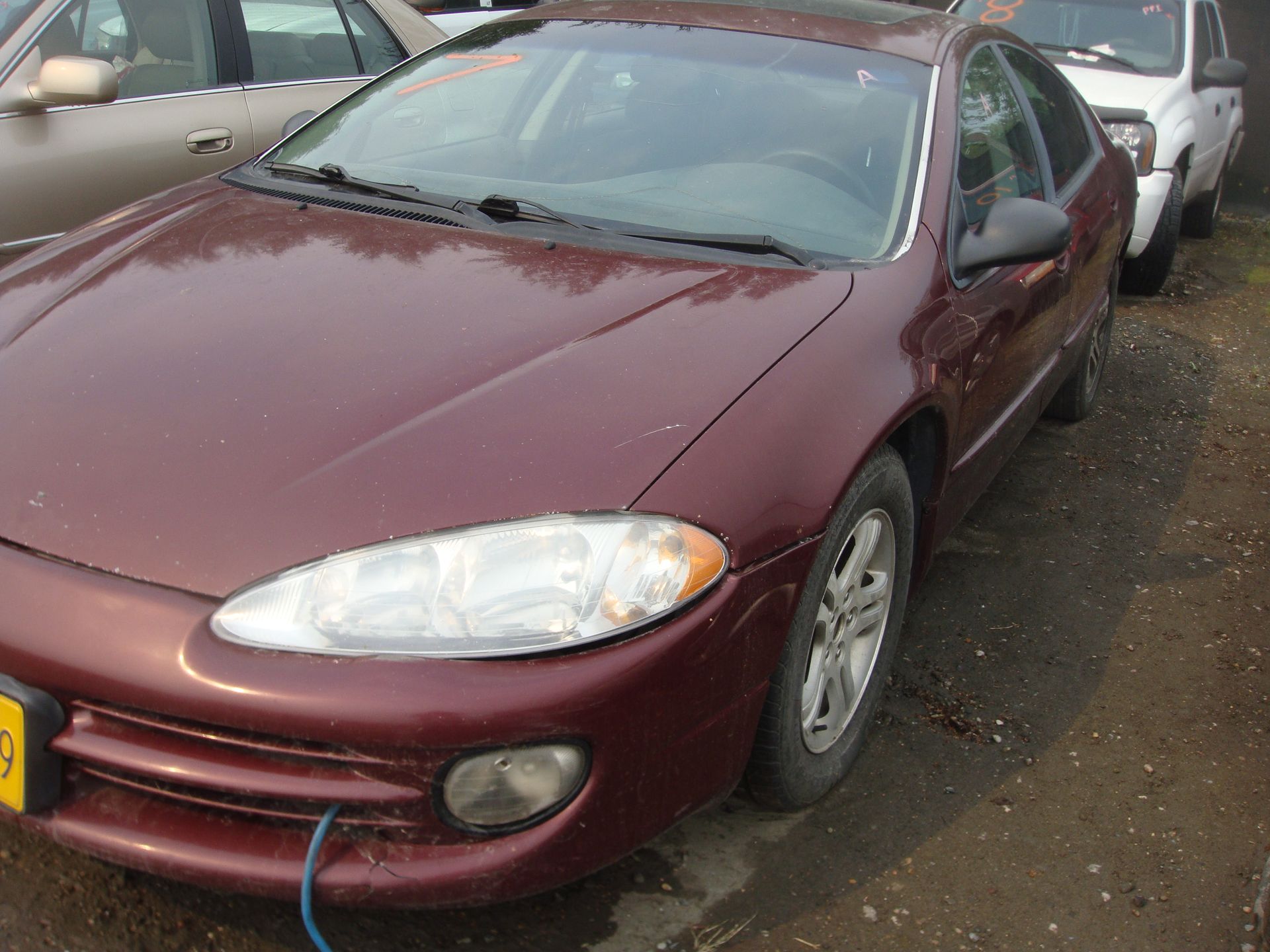 A red dodge intrepid is parked in a lot with other cars.