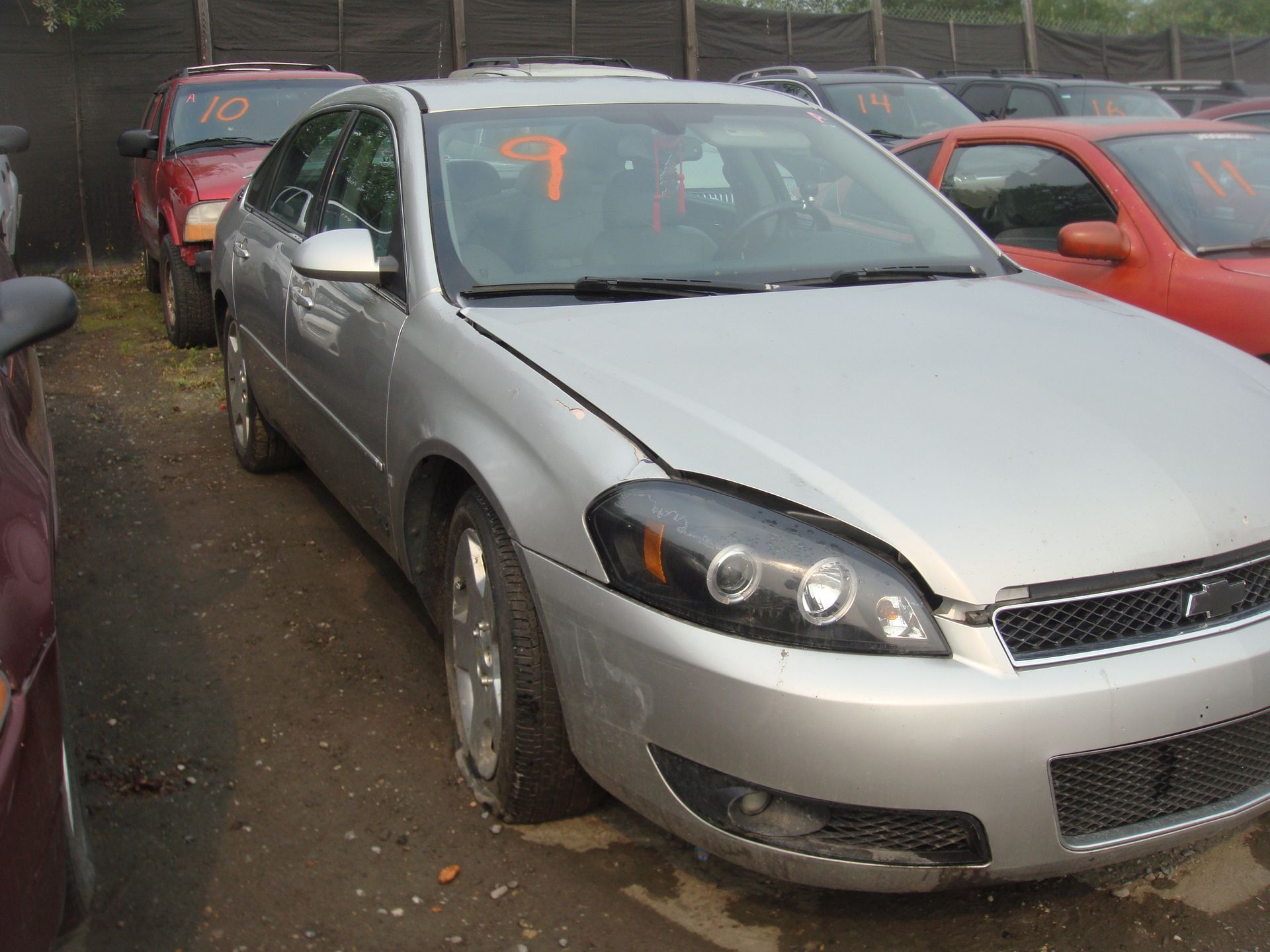 A silver car is parked in a lot with other cars