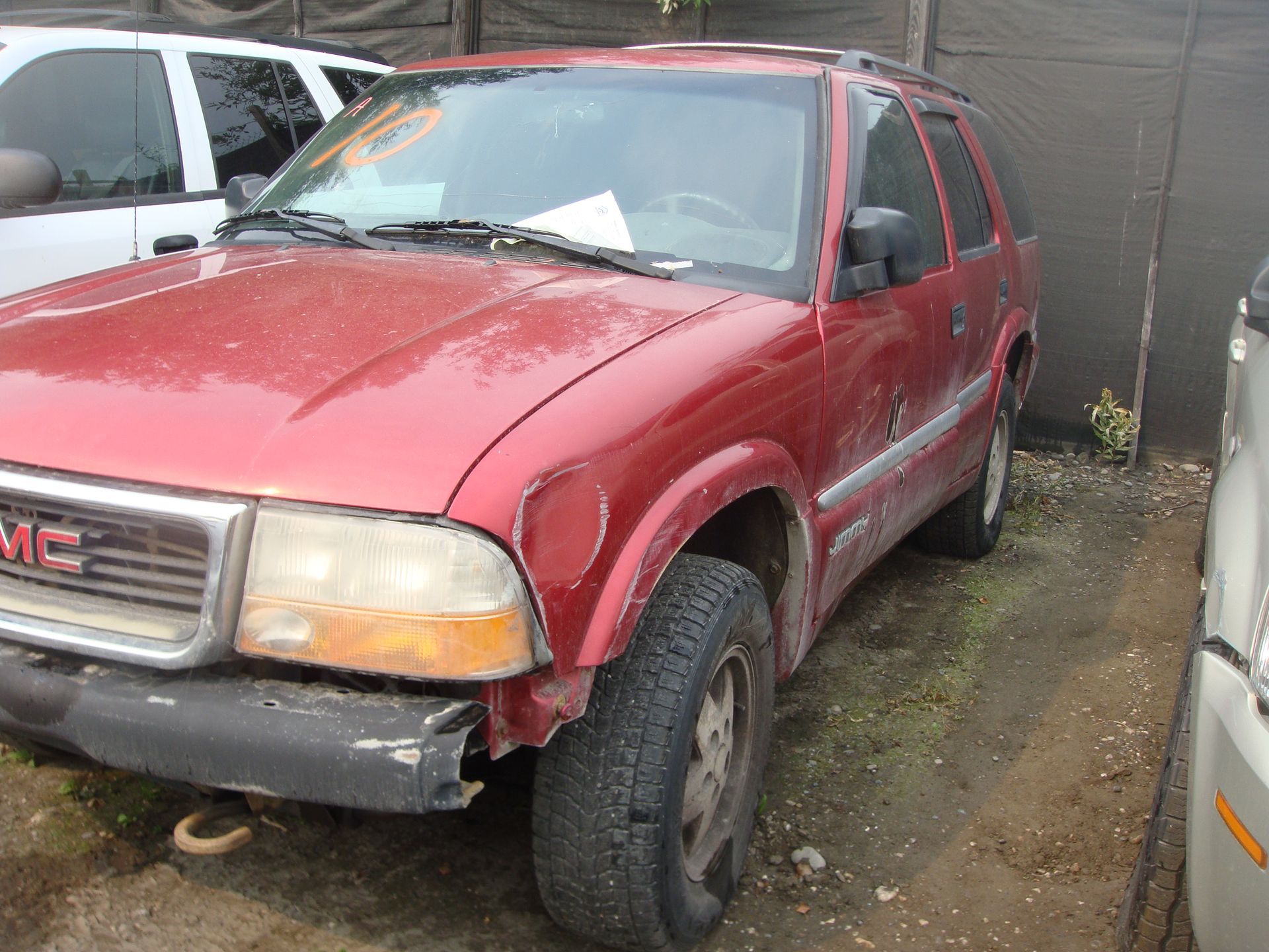 A red gmc sierra is parked in a dirt lot