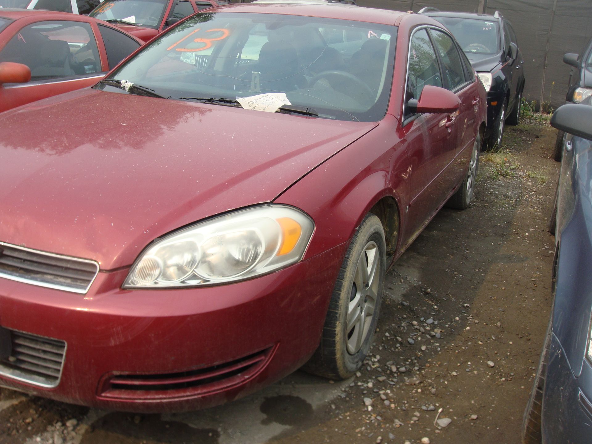 A red car is parked in a lot with other cars