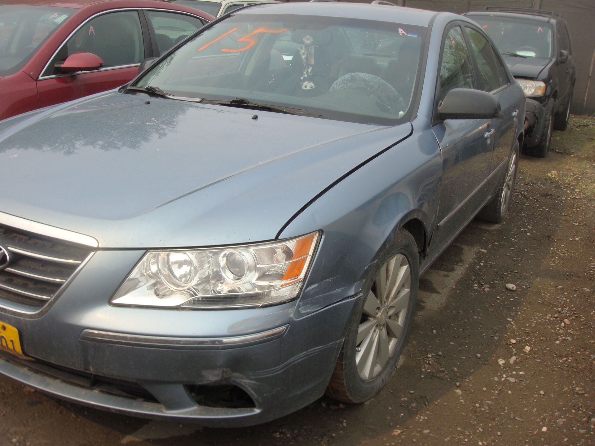 A blue hyundai sonata is parked next to a red car