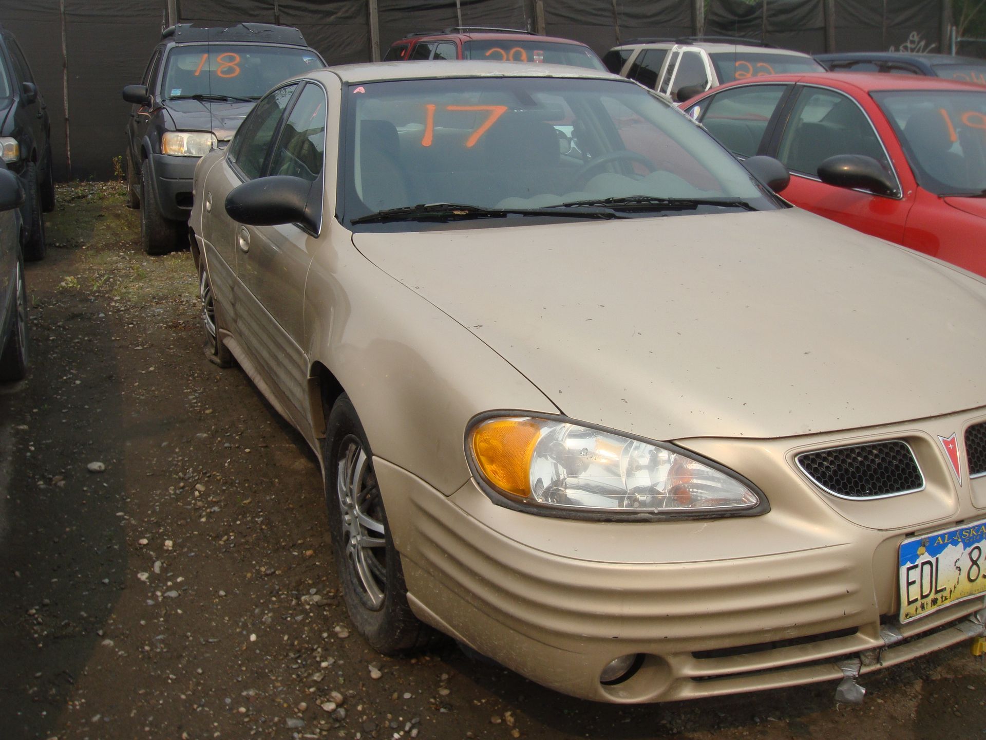 A gold pontiac grand prix is parked in a lot