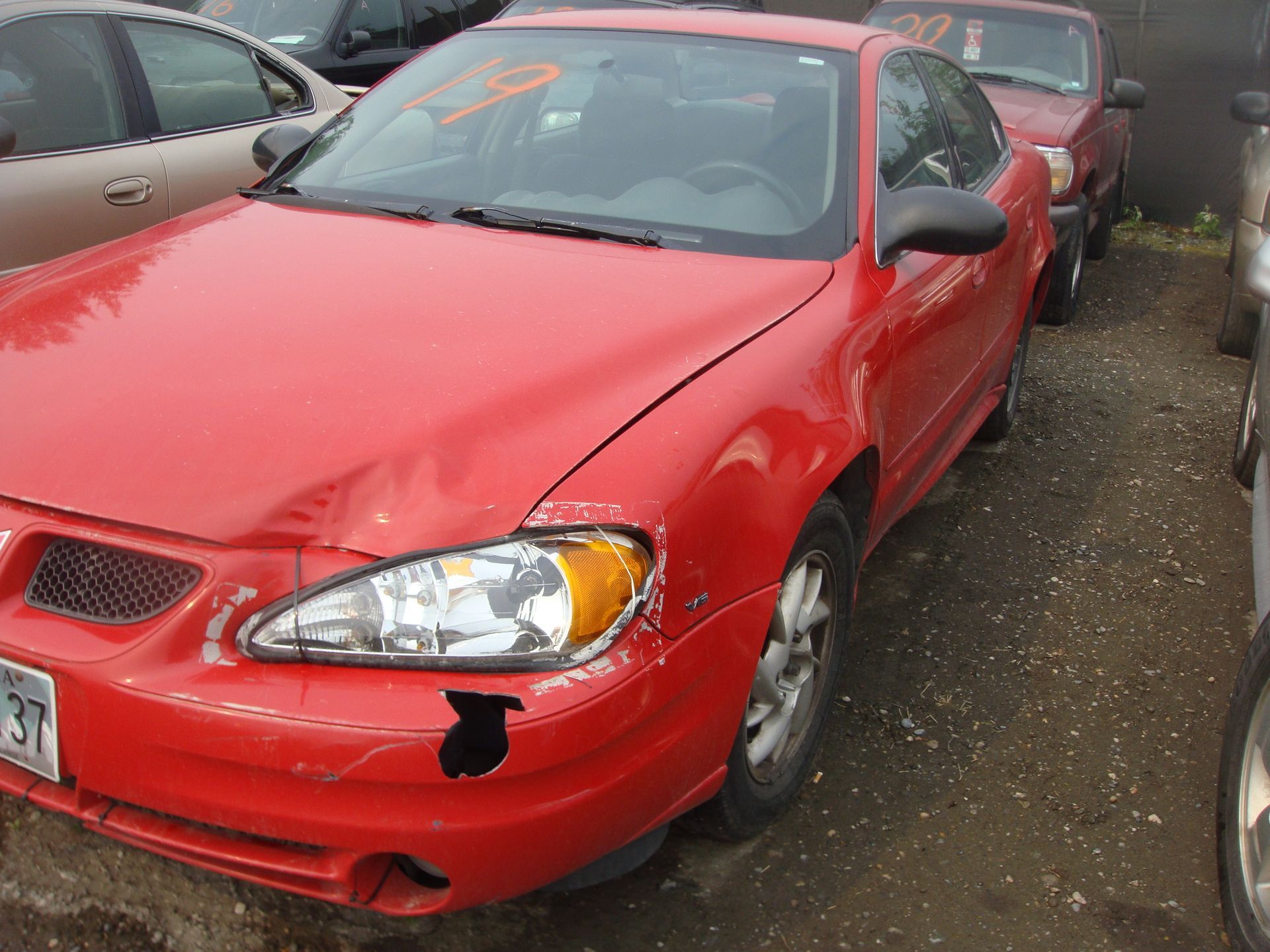 A red car is parked in a lot with other cars