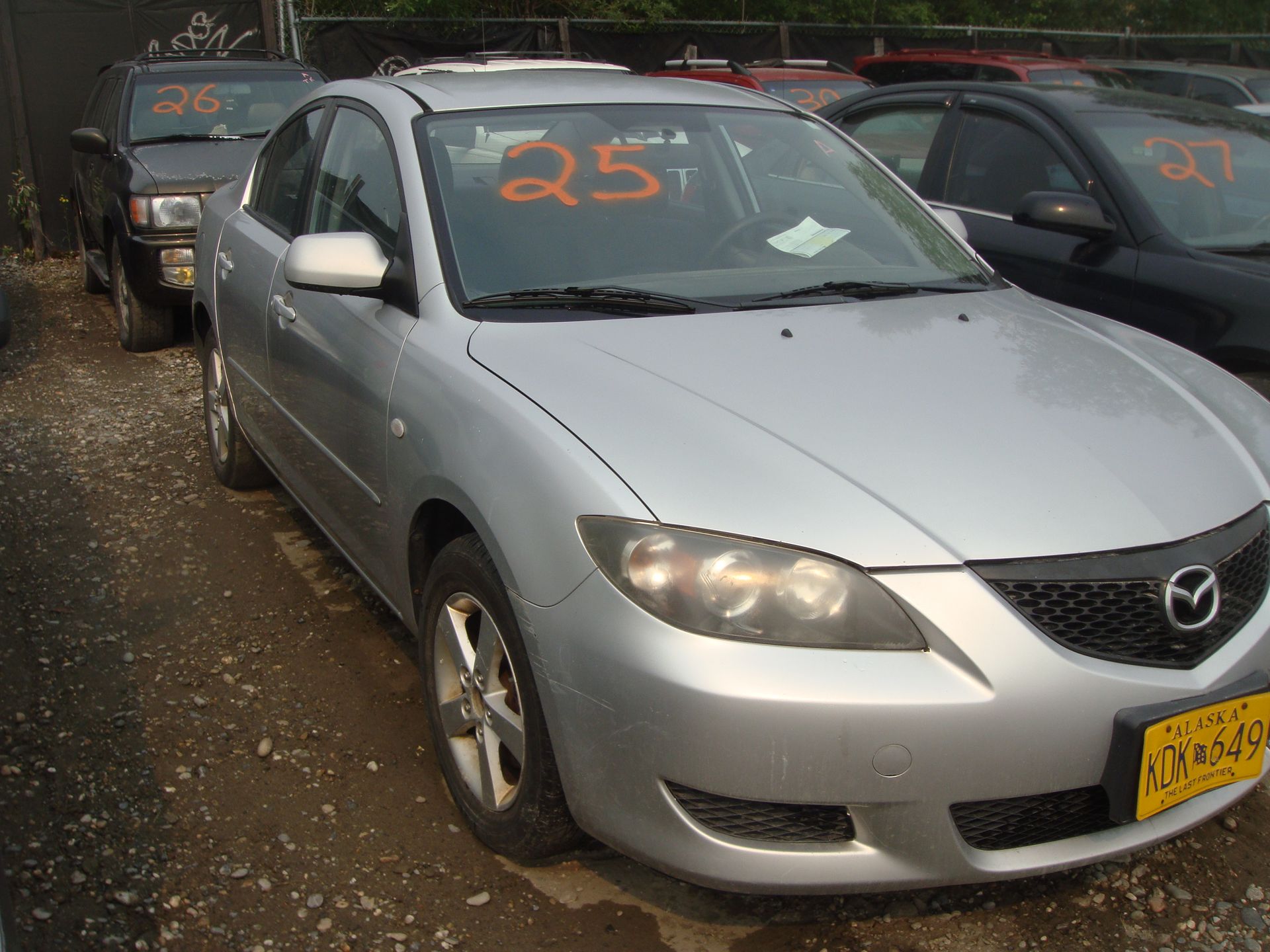 A silver car with the number 25 on the windshield