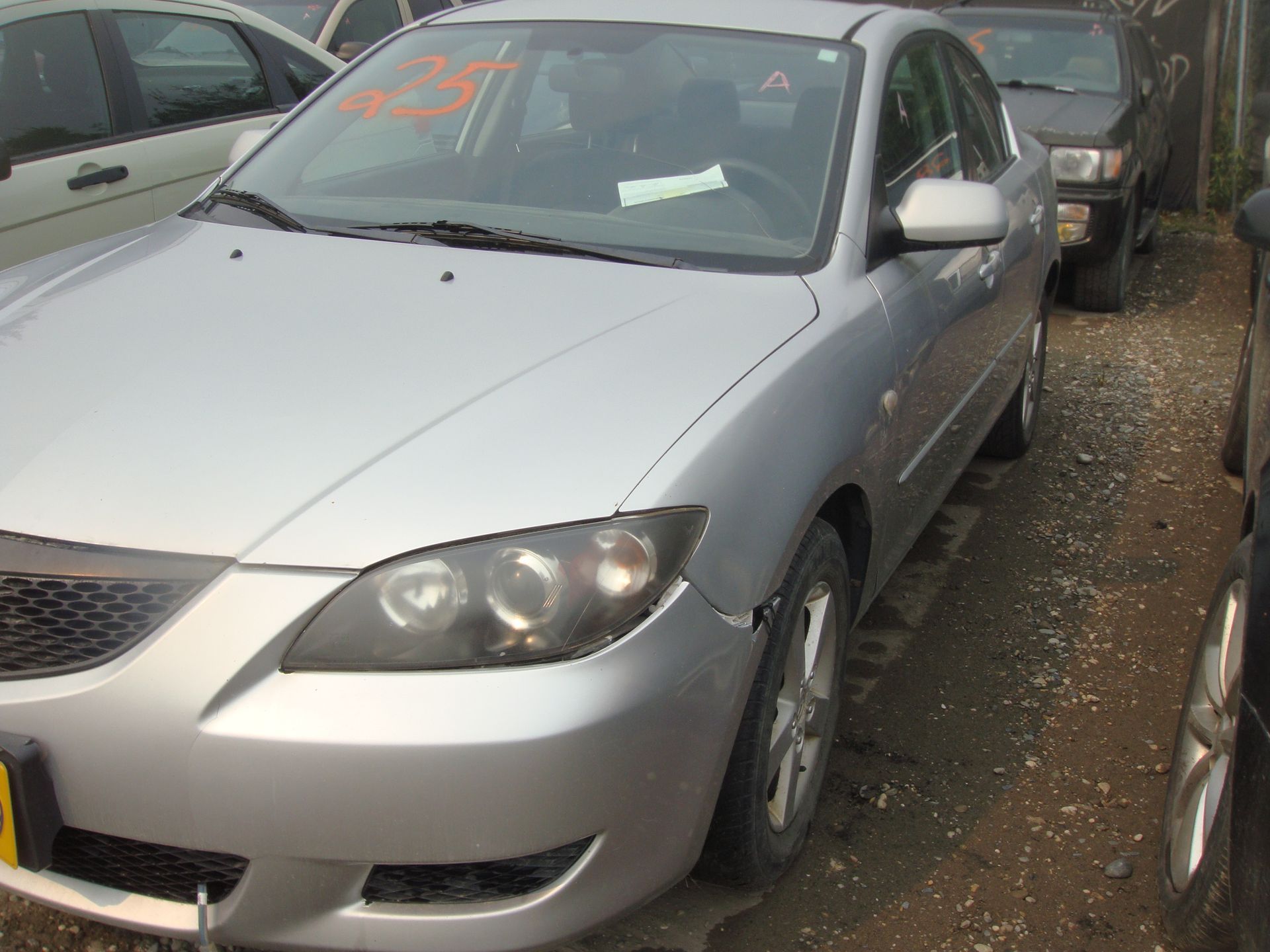 A silver car is parked in a lot with other cars