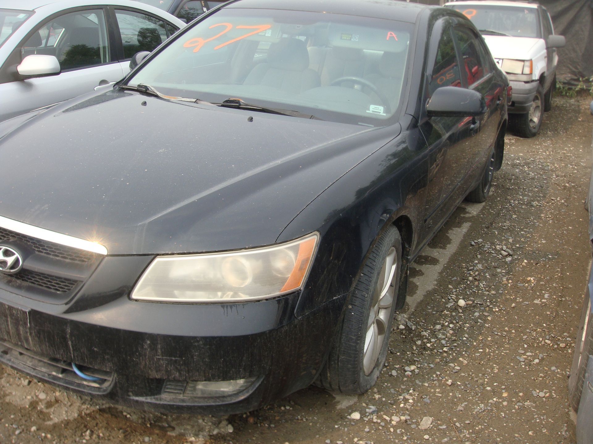 A black hyundai sonata is parked in a gravel lot