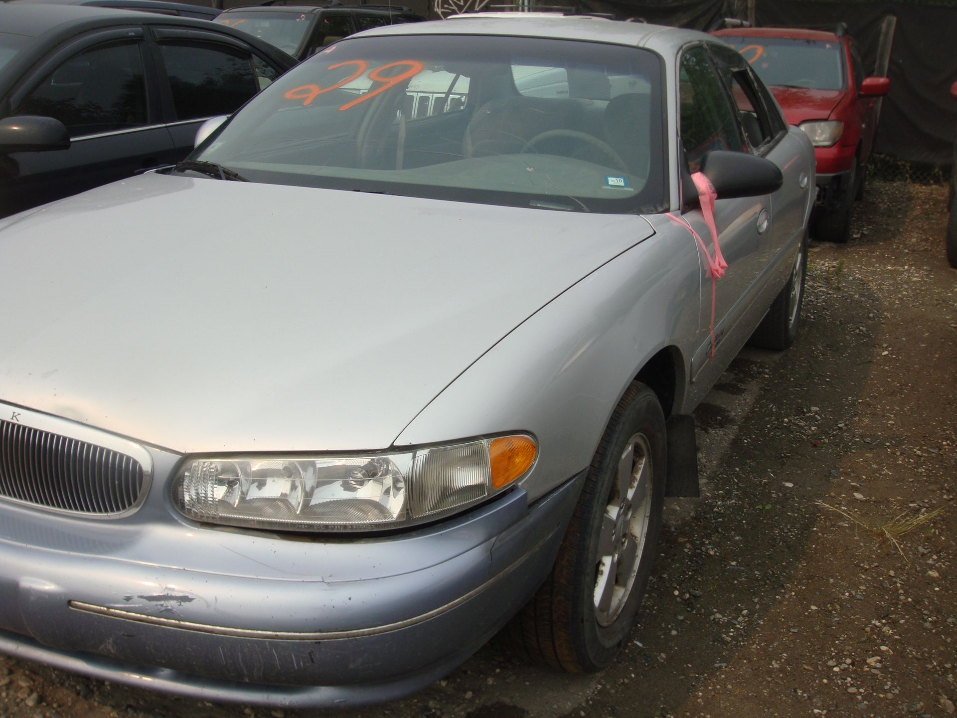 A silver car with a pink ribbon on the windshield