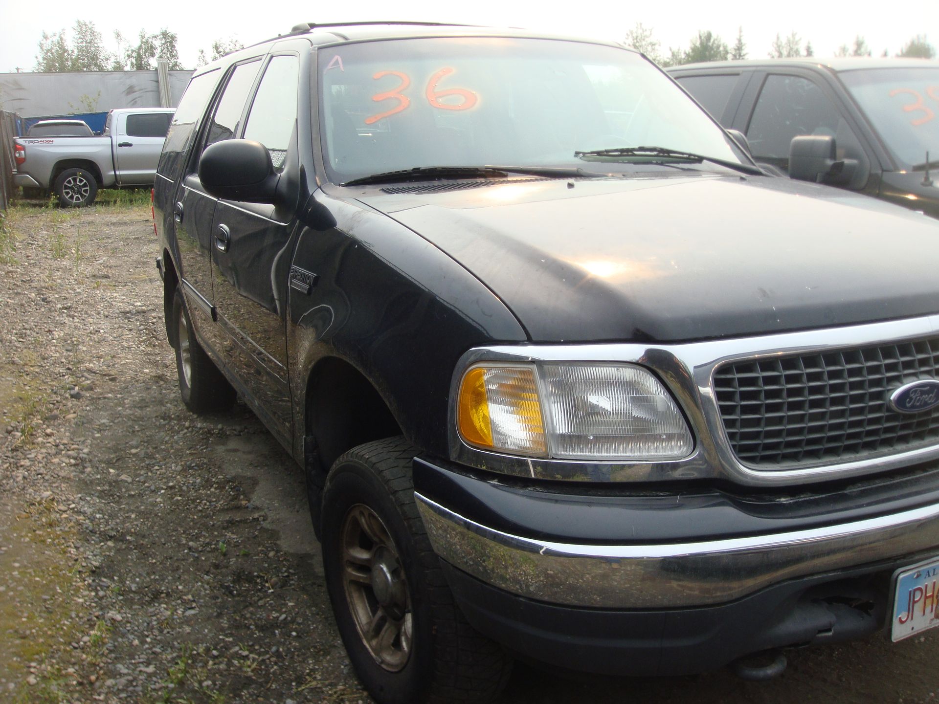 A black ford expedition is parked in a gravel lot.