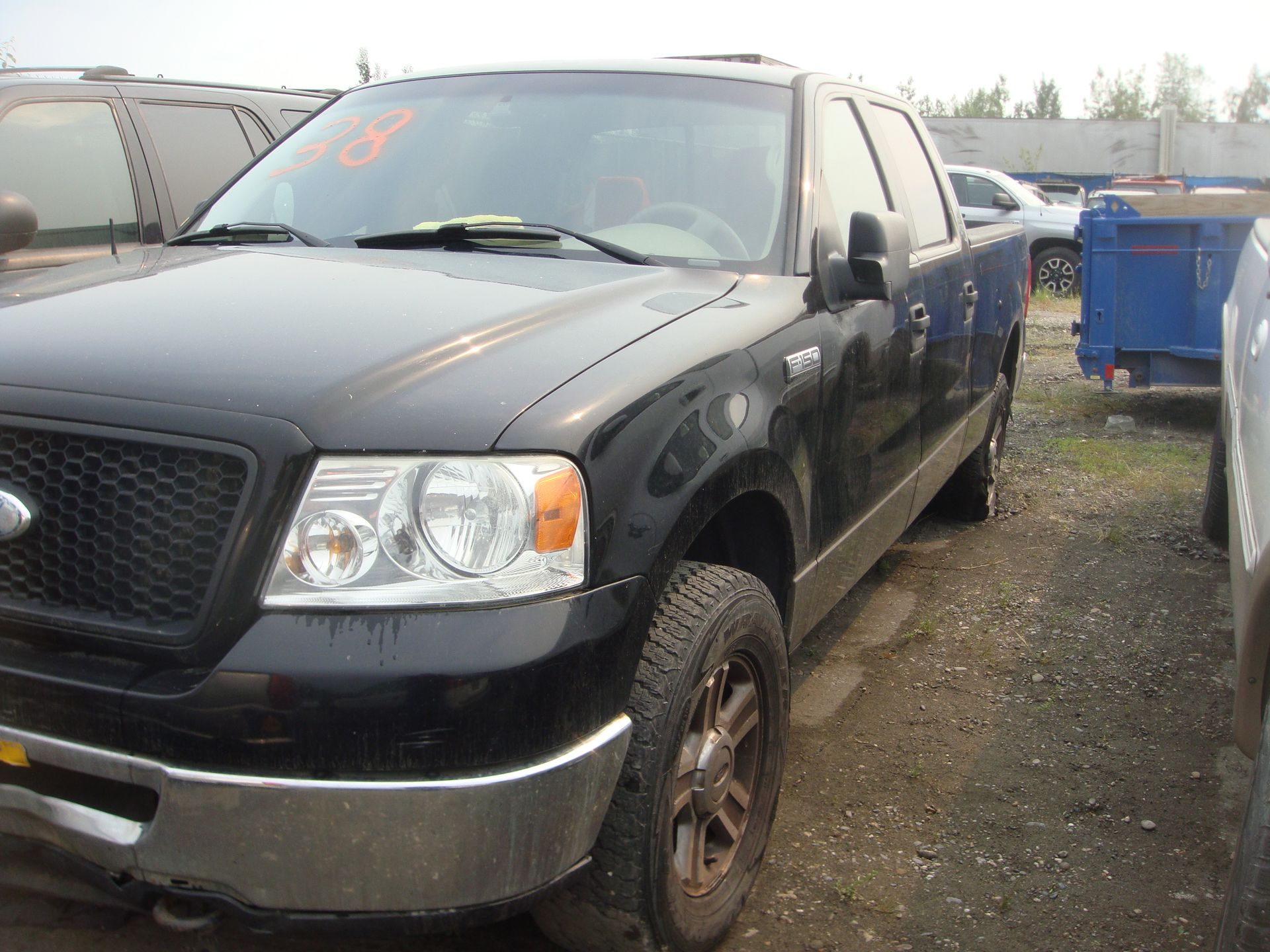 A black ford truck is parked in a gravel lot