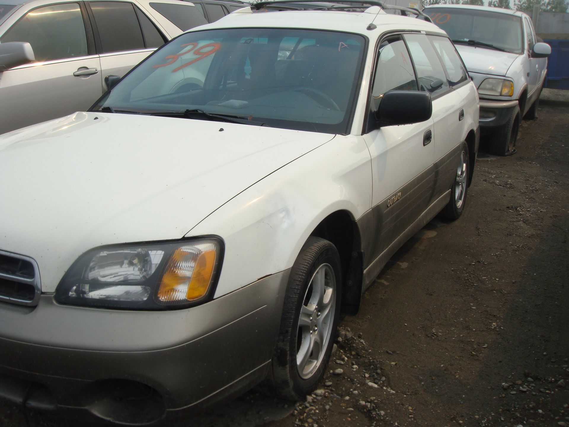 A white suv is parked in a lot with other cars