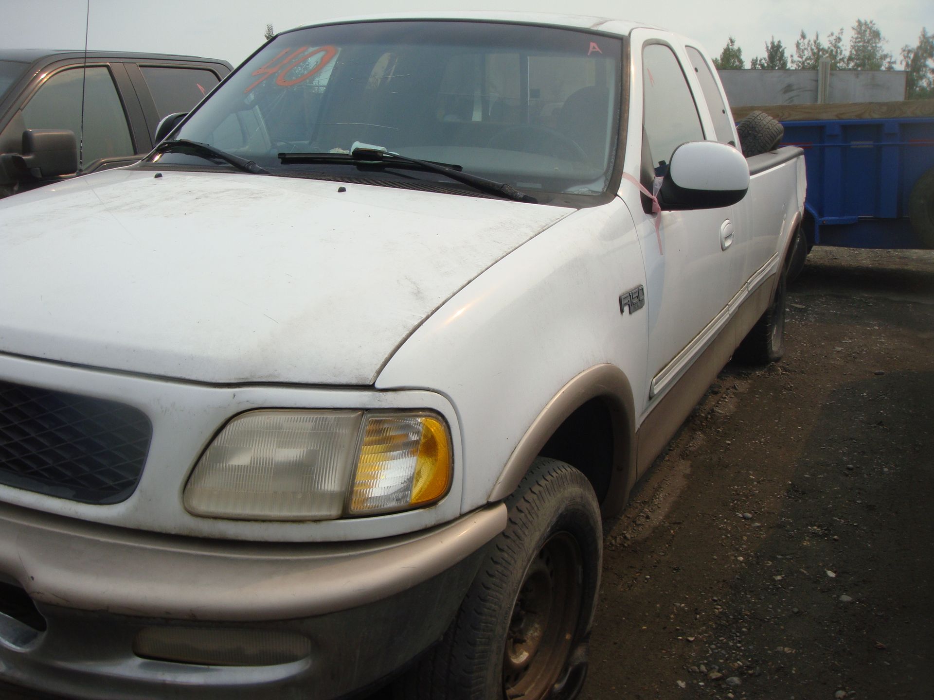 A white truck is parked in a gravel lot