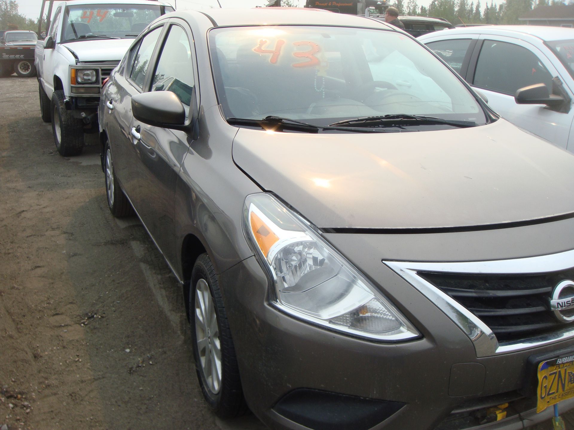 A nissan car is parked in a lot with other cars