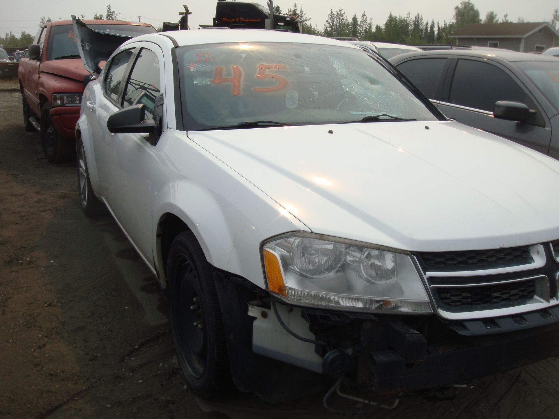 A white dodge avenger is parked in a lot